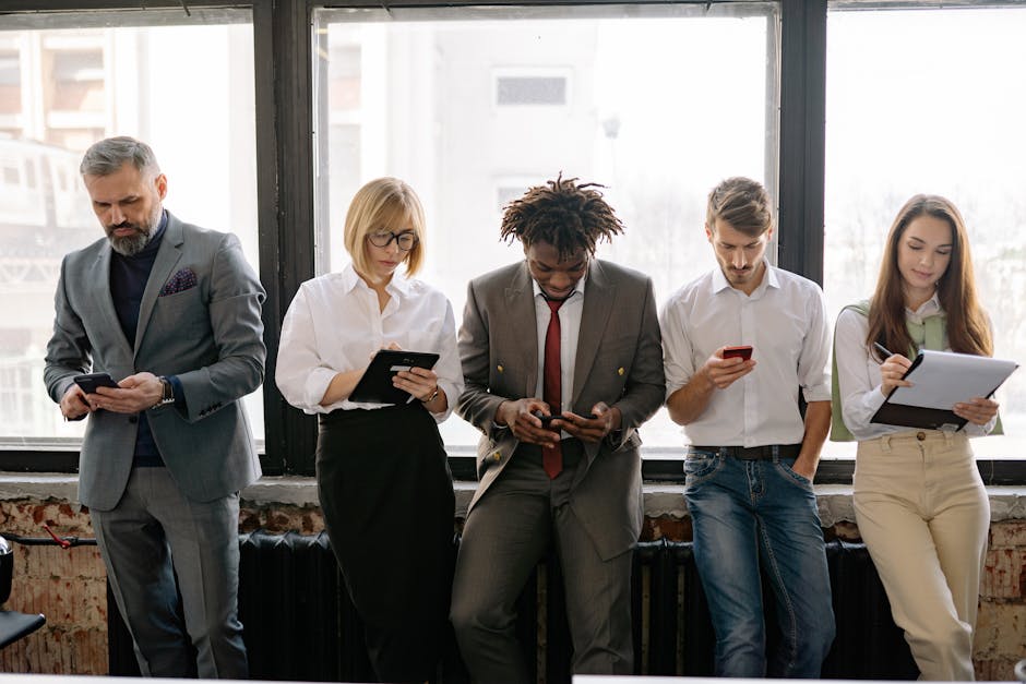 A diverse group of colleagues using mobile devices in an office setting.
